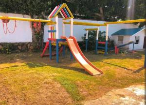 a playground with a slide in a yard at Cabaña cerca a la playa, con piscina, en playa Mendoza atlántico. in Puerto Colombia