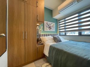 een slaapkamer met een bed en een grote houten kast bij SMDC Fame Residence luxurious family suite condo near mrt in Manilla
