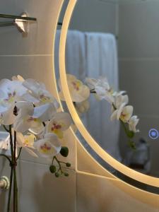 een bos witte orchideeënbloemen voor een spiegel bij SMDC Fame Residence luxurious family suite condo near mrt in Manilla