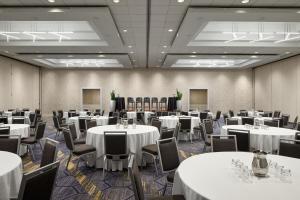 Cette chambre est dotée de tables, de chaises et de linge de maison blanc. dans l'établissement BWI Airport Marriott, à Linthicum