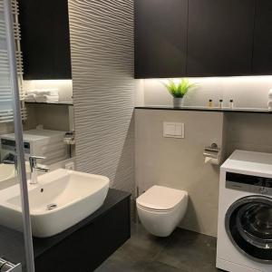 een badkamer met een wastafel, een toilet en een wasmachine bij Central Park Apartment in Łódź
