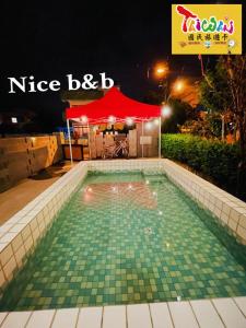 una piscina con una tienda roja en el fondo en 充電樁 羅東好民宿Cloud BnB 3 雲朵朵3館 免費洗衣機 烘衣機 星巴克咖啡豆 國旅特約店 en Yilan City