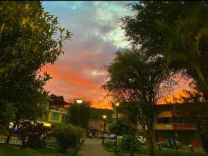 einen Sonnenuntergang über einer Straße mit Bäumen und Gebäuden in der Unterkunft El refugio de los viajeros in Quito