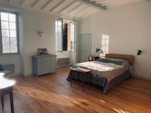 een slaapkamer met een bed, een dressoir en ramen bij Bourg sur Gironde in Bourg-sur-Gironde