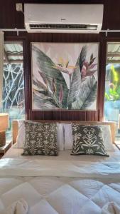 a bed with two pillows and a painting above it at Rumah Aggrek@Zaki’s Residence, Marang, Terengganu in Kampong Ru Lima