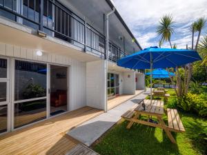 eine Terrasse mit einem Picknicktisch und einem Sonnenschirm in der Unterkunft The Captains Motel in Russell