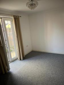 ein leeres Zimmer mit einem Kronleuchter und einem Fenster in der Unterkunft A spacious house in Kent in Sittingbourne