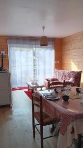 a living room with a table and a couch at MAISON OSSATURE BOIS in La Bourboule