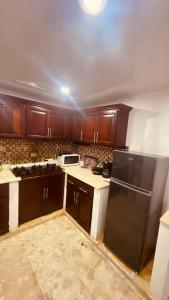 a kitchen with wooden cabinets and a black refrigerator at Mar azul 401 in San Felipe de Puerto Plata