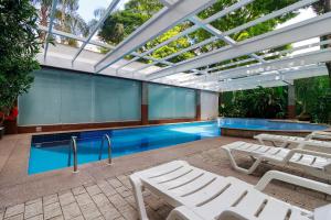 a pool with white lounge chairs and a swimming pool at Flat Executivo Verbo Divino in São Paulo