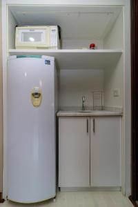 a small kitchen with a refrigerator and a microwave at Flat Executivo Verbo Divino in Sao Paulo