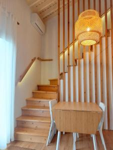 einen Esstisch mit einem Kronleuchter und einer Treppe in der Unterkunft Casas da Chaminé Eco Country Lodge in Nordeste