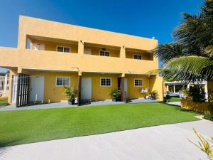 um grande edifício amarelo com um pátio verde em The Gold Vacation Apartments em Santa Cruz