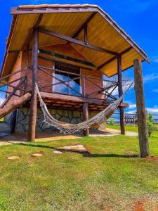 a wooden building with a hammock in the grass at Chalet di Alta Montagna in Santo Antônio do Pinhal