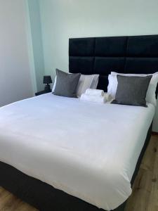 a large white bed with a black headboard and pillows at Stylish apartments in Gaborone