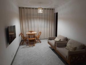 ein Wohnzimmer mit einem Sofa und einem Tisch in der Unterkunft Apartamento perto da Orla de Atalaia in Aracaju