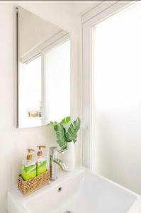 a white bathroom with a sink and a mirror at Tropical Oasis On The Water Crown Point in San Diego