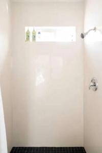 a white bathroom with a shower with a black tile floor at Tropical Oasis On The Water Crown Point in San Diego