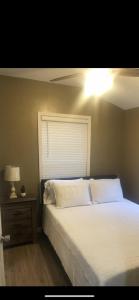 1 dormitorio con cama blanca y mesita de noche en Louisiana State Cabin en West Point