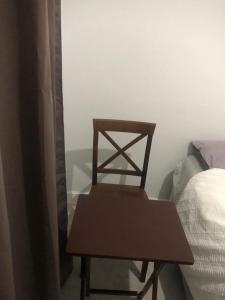 a wooden chair sitting in a room next to a bed at Single room in willesden in London