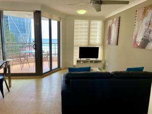 sala de estar con sofá y TV de pantalla plana en Warringa Surf Holiday Apartments, en Gold Coast