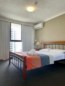 1 dormitorio con cama y ventana grande en Warringa Surf Holiday Apartments, en Gold Coast