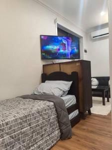 a bedroom with a bed and a flat screen tv on the wall at Short-long term Private Smart modern studio in Jamboree Heights