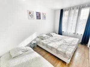 2 camas en un dormitorio con cortinas azules en Appartement proche Roissy CDG, Parc expos de Villepinte, Disneyland, Paris, Astérix, en Le Thillay