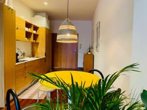 een eetkamer met een gele tafel en een keuken bij Ferreira Borges Nomadic Ap. C in Porto