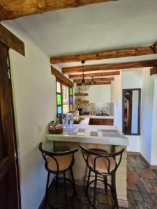 a kitchen with two bar stools and a counter at Hospedaje Resguardo Real in Ráquira