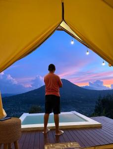un hombre de pie en una cubierta mirando la puesta de sol en Pinggan luxury camp, en Gretek
