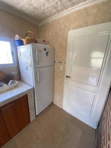 eine Küche mit einem weißen Kühlschrank und einer Tür in der Unterkunft Casa en la montaña con gran vista al valle y lago in El Mollar