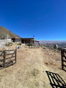 ein Haus auf einem Hügel mit einem Zaun in der Unterkunft Casa en la montaña con gran vista al valle y lago in El Mollar