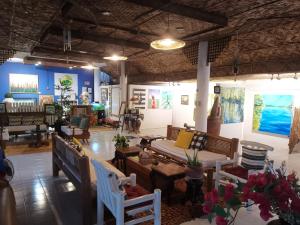 La Vida Hostel Samal Island في سمَل: غرفة بها كراسي وطاولات ولوحات على الجدران