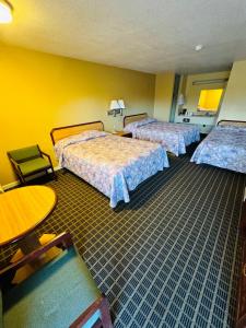 um quarto de hotel com duas camas e uma mesa em Mount Whitney Motel em Lone Pine