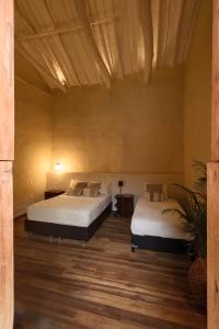 two beds sitting in a room with wooden floors at CASA JUANA BARICHARA in Barichara