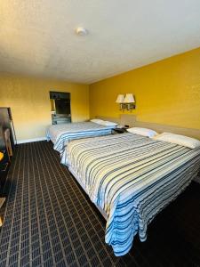2 bedden in een hotelkamer met gele muren bij Mount Whitney Motel in Lone Pine