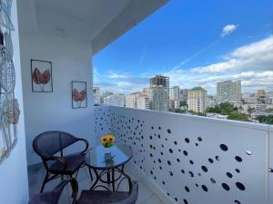 een balkon met een tafel en stoelen en een skyline van de stad bij Comfy Business Apartment in Piantini *LuxuryStay* in Santo Domingo