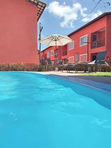 a swimming pool in front of a red building at Linda Casa de Veraneio em Monte Gordo/Ba in Camacari