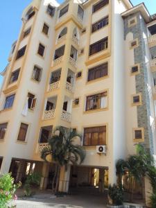 a large white building with palm trees in front of it at Serena Beach View Apartment in Mombasa