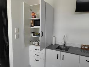 una cocina con armarios blancos y fregadero en Marina Views en One Tree Point
