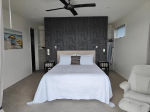 a bedroom with a white bed and a ceiling fan at Marina Views in One Tree Point