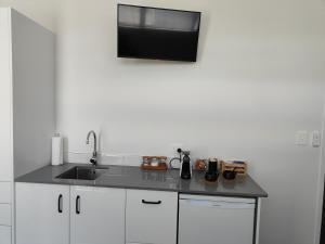 cocina con fregadero y TV en la pared en Marina Views, en One Tree Point