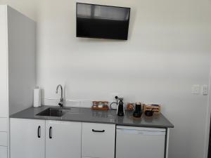 a kitchen with a sink and a tv on the wall at Marina Views in One Tree Point