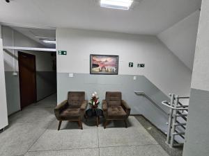two chairs and a table in a hallway at Hotel Avelar in Ribeirão das Neves