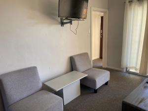Zimmer mit 2 Stühlen, einem Tisch und einem TV in der Unterkunft Blackheath Holiday Cabins in Blackheath