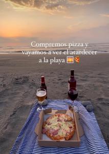 a pizza in a box on the beach with two drinks at Hotel Dreimar in Cartagena de Indias