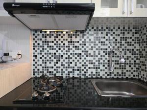 a kitchen counter with a sink and a stove at Apt Bassura Studio Tower F w/ Pool, Wi-Fi & Netflx in Jakarta