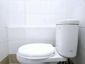 a white toilet in a white tiled bathroom at Apt Bassura Studio Tower F w/ Pool, Wi-Fi & Netflx in Jakarta +5 photos