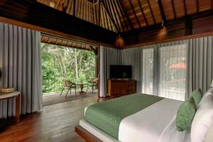 a bedroom with a bed and a large window at AnandaDara Ubud in Ubud